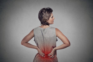 young woman with backache lower back pain colored in red